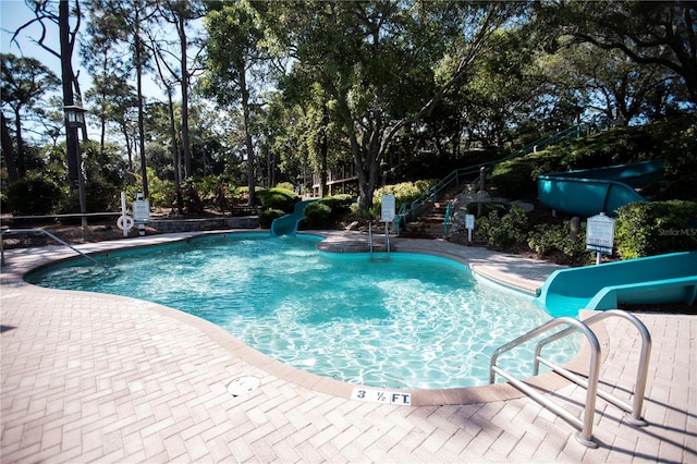 view of pool with a water slide and a patio