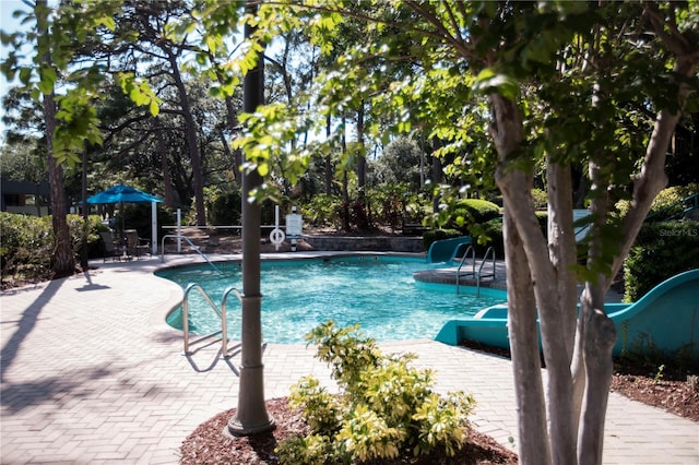 view of pool featuring a water slide and a patio