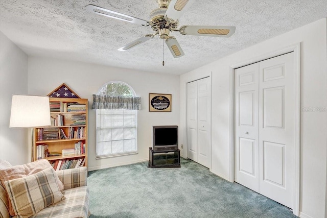 living area featuring a textured ceiling, ceiling fan, and carpet flooring