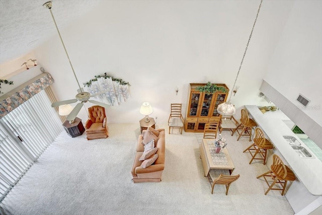 living room with carpet, ceiling fan, high vaulted ceiling, and a textured ceiling