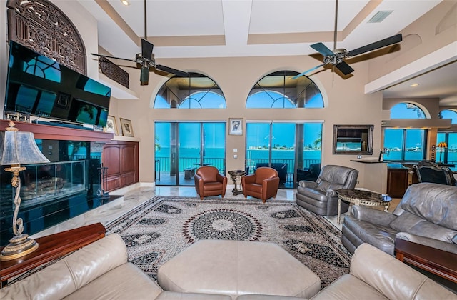 tiled living room featuring a high ceiling, ceiling fan, and a fireplace