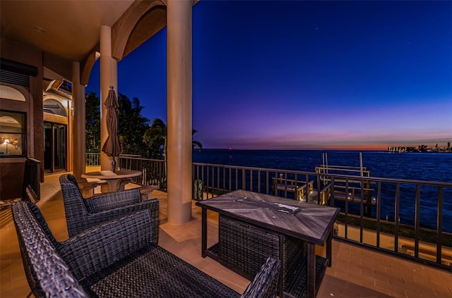 patio terrace at dusk with a water view and a balcony