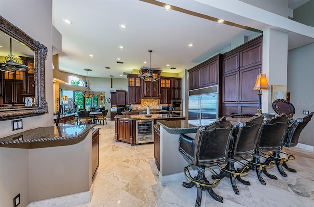 kitchen featuring wine cooler, stainless steel appliances, decorative light fixtures, light tile floors, and a breakfast bar