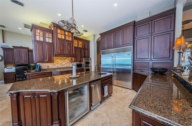 kitchen with stainless steel appliances, light tile flooring, beverage cooler, and a kitchen island with sink