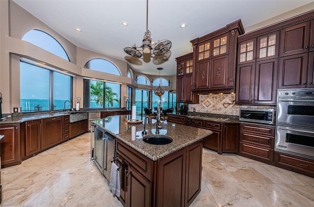 kitchen featuring light tile flooring, pendant lighting, dark stone countertops, a kitchen island, and appliances with stainless steel finishes