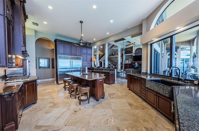 kitchen featuring a healthy amount of sunlight, a kitchen island with sink, and dark stone countertops