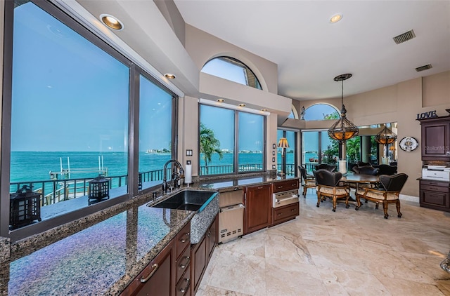 bathroom featuring tile floors, sink, a towering ceiling, and a water view