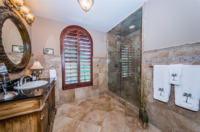 bathroom featuring a shower with shower door, tile flooring, oversized vanity, and tile walls