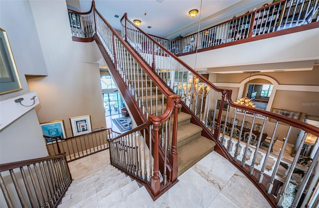 stairs with tile floors and a towering ceiling