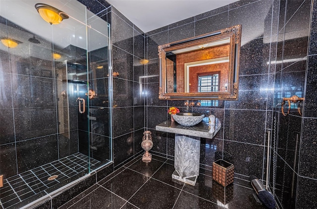 bathroom with tile walls, sink, a shower with door, and tile floors