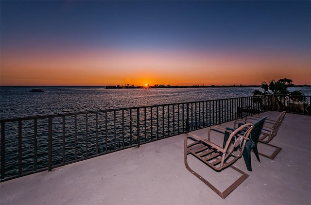 patio terrace at dusk featuring a water view