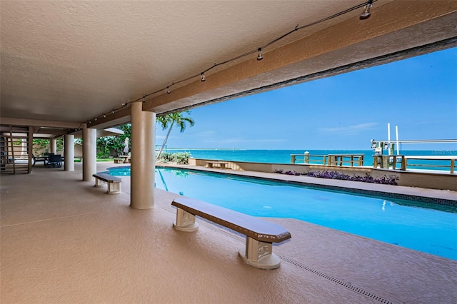 view of pool with a water view and a patio area