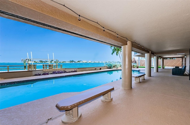 view of swimming pool with a water view and a patio area