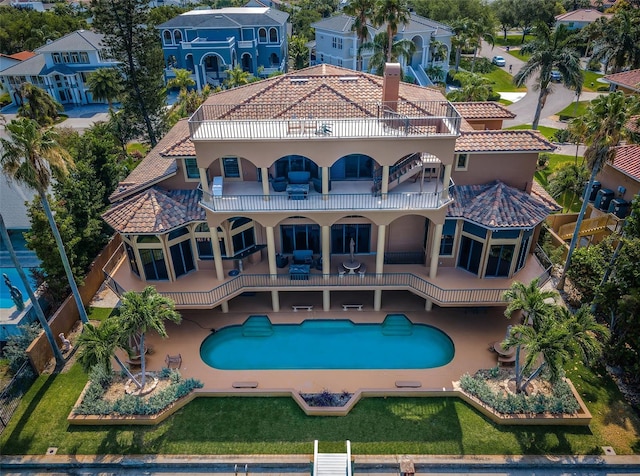 back of property featuring a patio area, a balcony, and a lawn