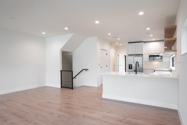 kitchen with sink, appliances with stainless steel finishes, white cabinets, and light wood-type flooring