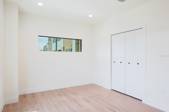 unfurnished bedroom featuring light hardwood / wood-style flooring and a closet