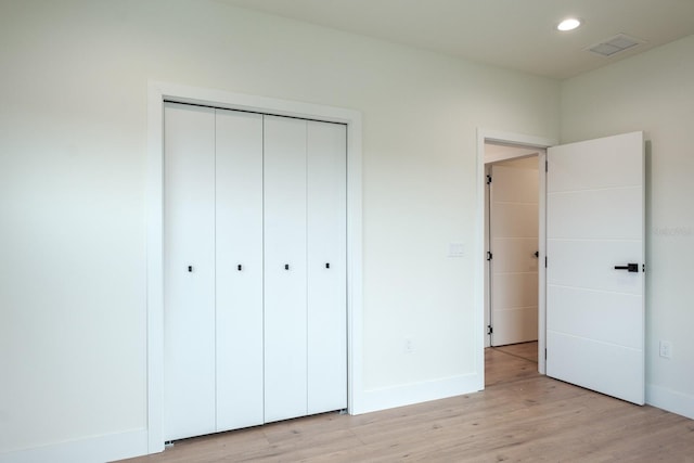 unfurnished bedroom with light hardwood / wood-style flooring and a closet