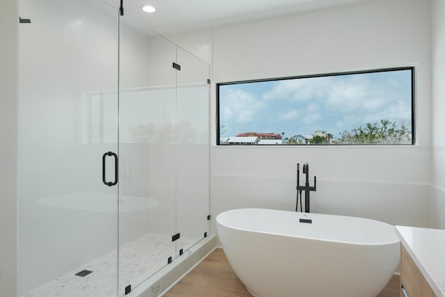 bathroom featuring plenty of natural light, shower with separate bathtub, tile walls, and hardwood / wood-style flooring