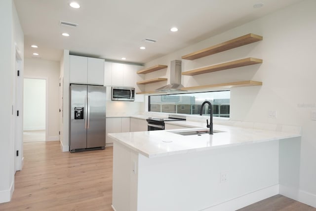 kitchen featuring light hardwood / wood-style floors, appliances with stainless steel finishes, white cabinetry, and kitchen peninsula