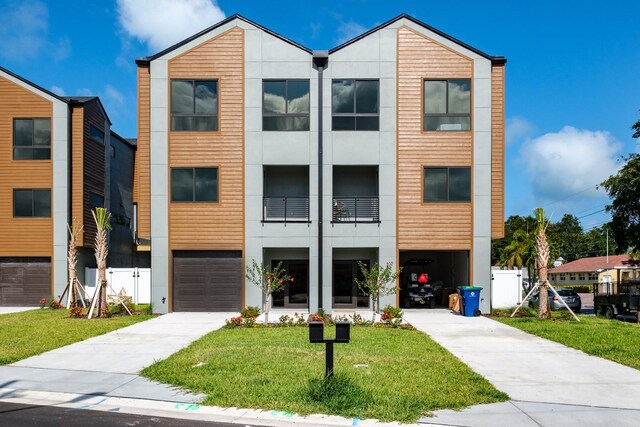 view of front facade featuring a balcony, a garage, and a front lawn