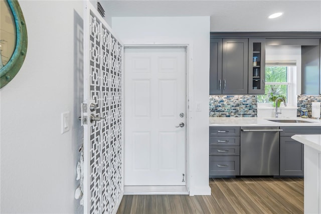 kitchen with dishwasher, sink, hardwood / wood-style flooring, and backsplash