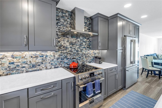 kitchen with stainless steel appliances, tasteful backsplash, gray cabinetry, and wall chimney exhaust hood