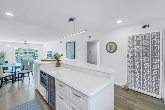 kitchen with a center island, white cabinets, beverage cooler, decorative light fixtures, and ceiling fan