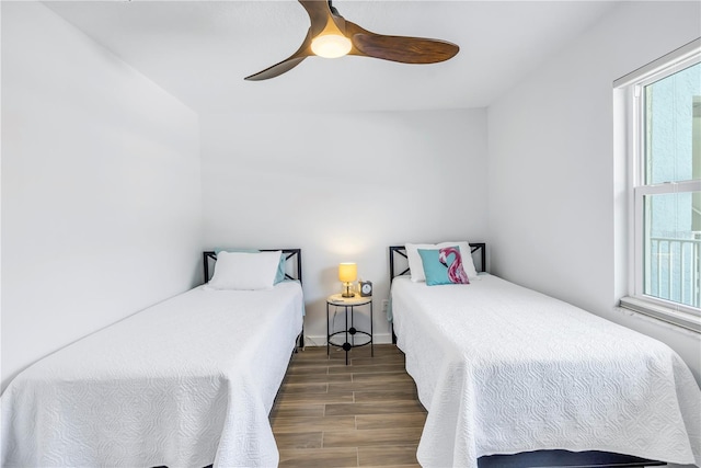 bedroom featuring ceiling fan, multiple windows, and dark hardwood / wood-style flooring