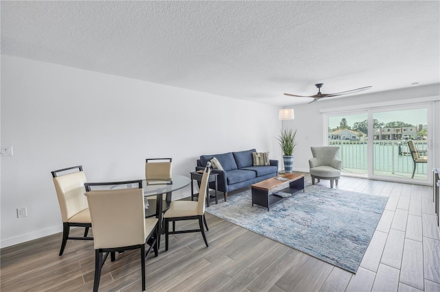 living room featuring ceiling fan, a textured ceiling, and hardwood / wood-style flooring