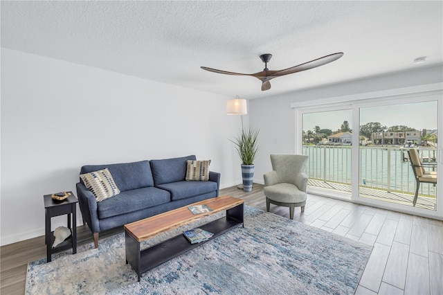 living room featuring hardwood / wood-style flooring, ceiling fan, and a textured ceiling