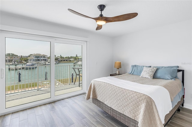 bedroom featuring ceiling fan, access to exterior, a water view, and wood-type flooring