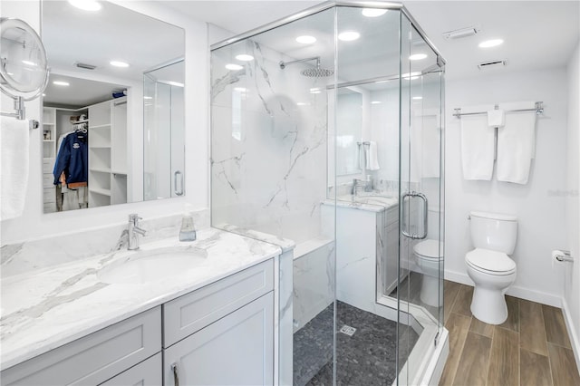 bathroom featuring wood-type flooring, an enclosed shower, vanity, and toilet