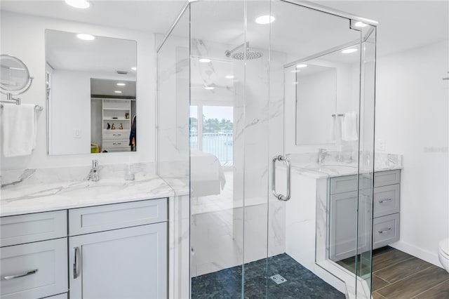 bathroom with wood-type flooring, a shower with shower door, large vanity, and toilet