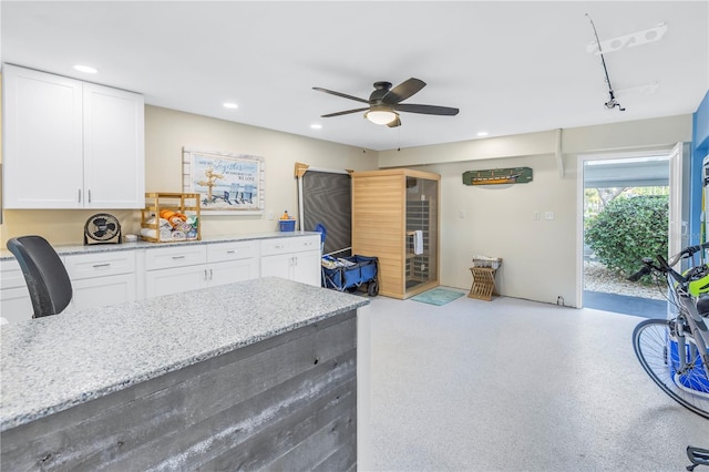 kitchen with light stone counters, ceiling fan, white cabinets, and rail lighting