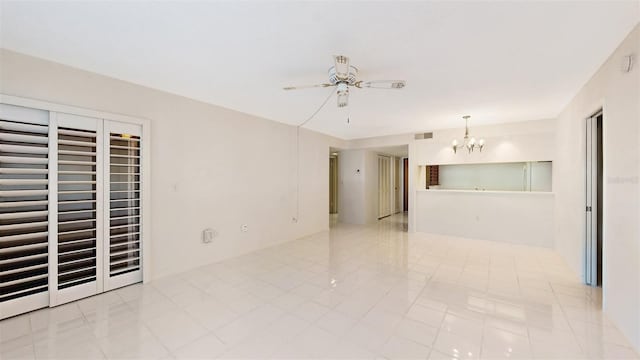 spare room featuring light tile flooring and ceiling fan with notable chandelier