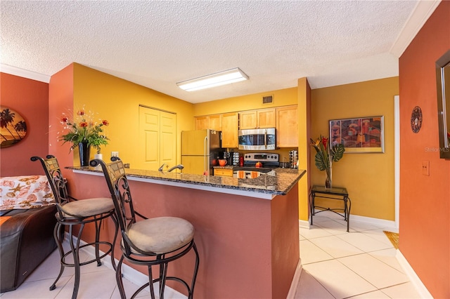 kitchen with dark stone counters, a textured ceiling, light tile floors, and appliances with stainless steel finishes