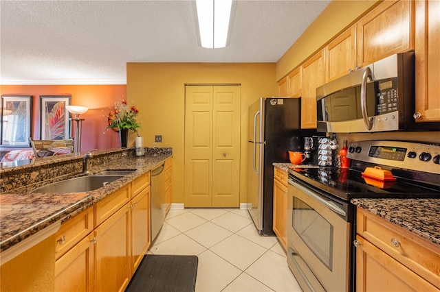 kitchen with dark stone counters, light tile flooring, a textured ceiling, sink, and appliances with stainless steel finishes