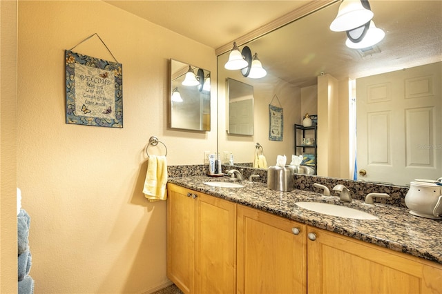 bathroom featuring oversized vanity, dual sinks, and a textured ceiling