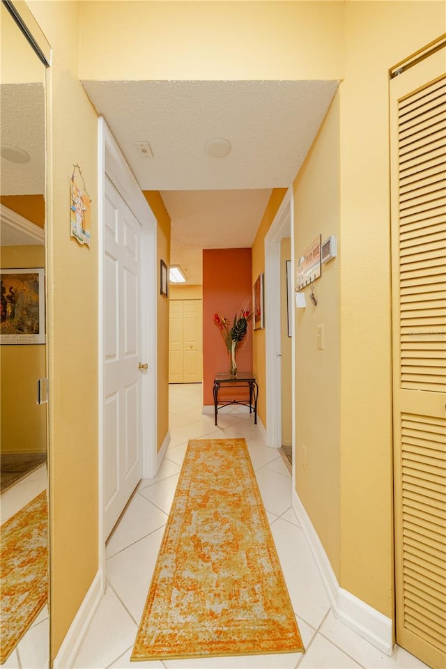 hall with light tile flooring and a textured ceiling