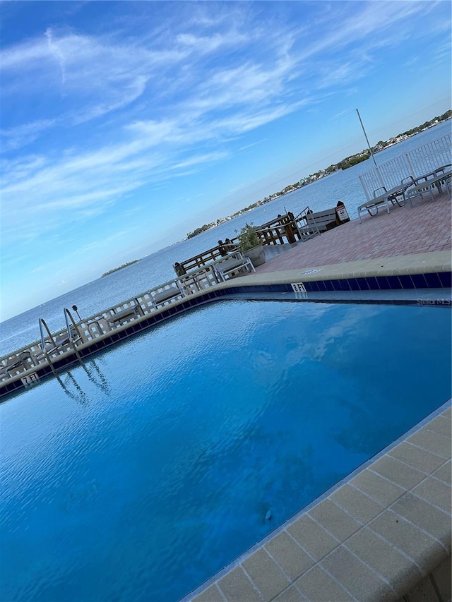 view of swimming pool featuring a water view and a dock