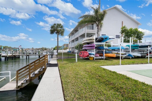 view of dock with a water view, a yard, and a balcony