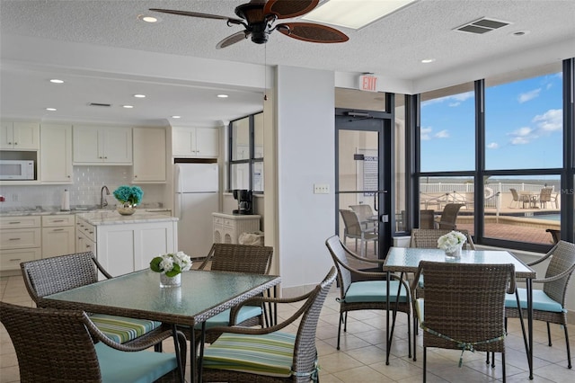 tiled dining space with ceiling fan, a textured ceiling, and sink