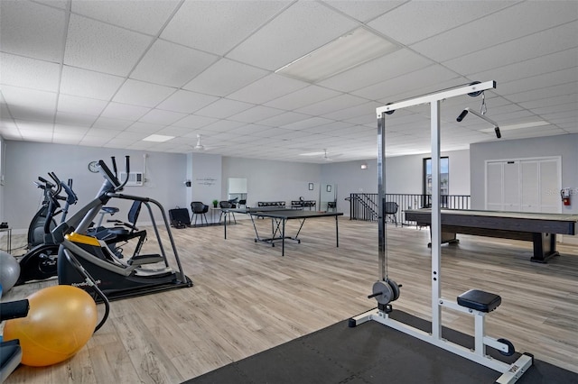 gym with billiards, light wood-type flooring, and a drop ceiling