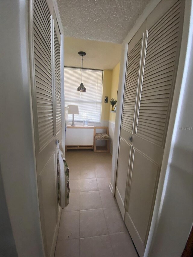 hall with tile flooring and a textured ceiling