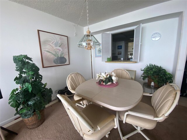 dining area featuring a chandelier, a textured ceiling, and carpet floors