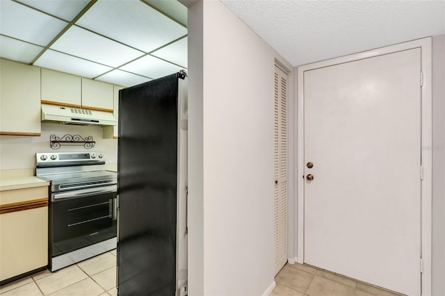 kitchen with light tile patterned flooring, black refrigerator, and electric stove