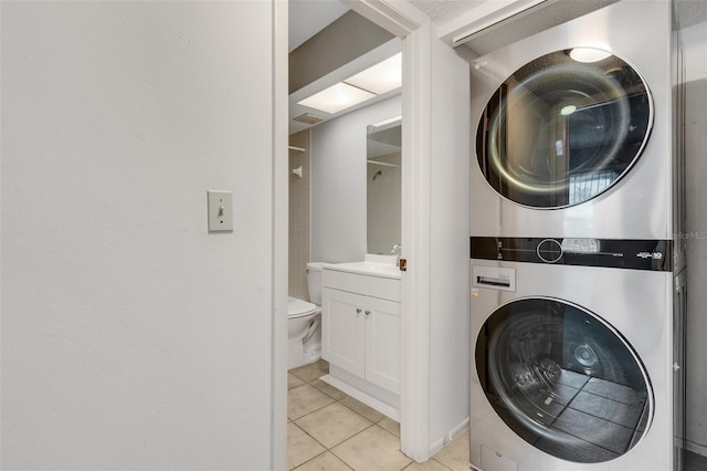 laundry area featuring light tile patterned flooring and stacked washer and dryer