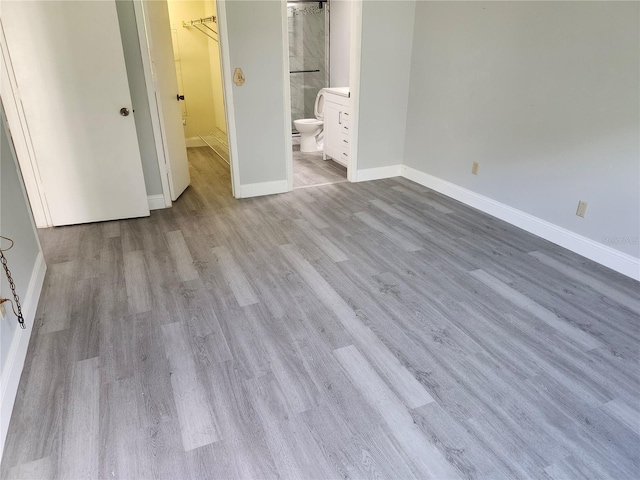 unfurnished bedroom featuring light hardwood / wood-style flooring, a walk in closet, a closet, and ensuite bath