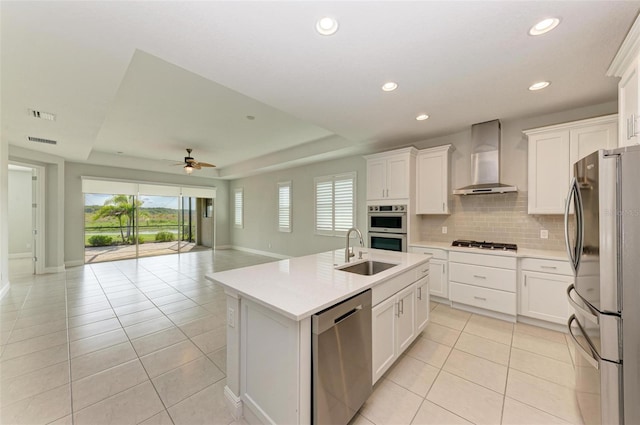 kitchen with ceiling fan, stainless steel appliances, backsplash, wall chimney exhaust hood, and sink