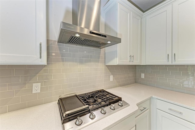 kitchen featuring white cabinetry, light stone countertops, stainless steel gas stovetop, wall chimney exhaust hood, and backsplash